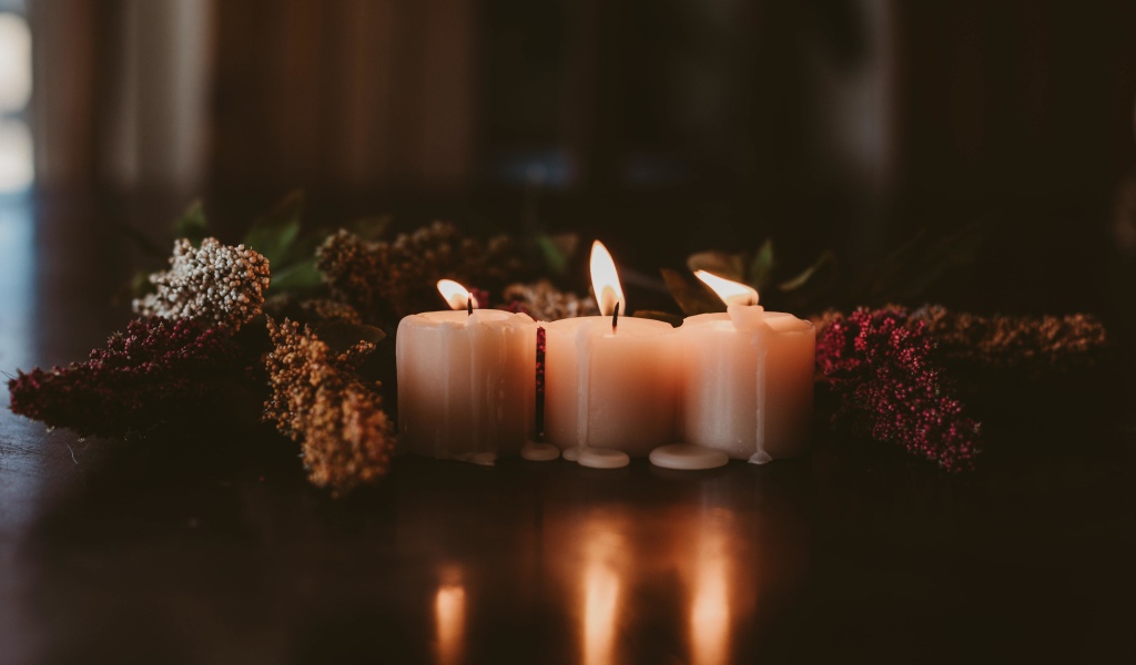 Зажженные свечи с цветами на полу