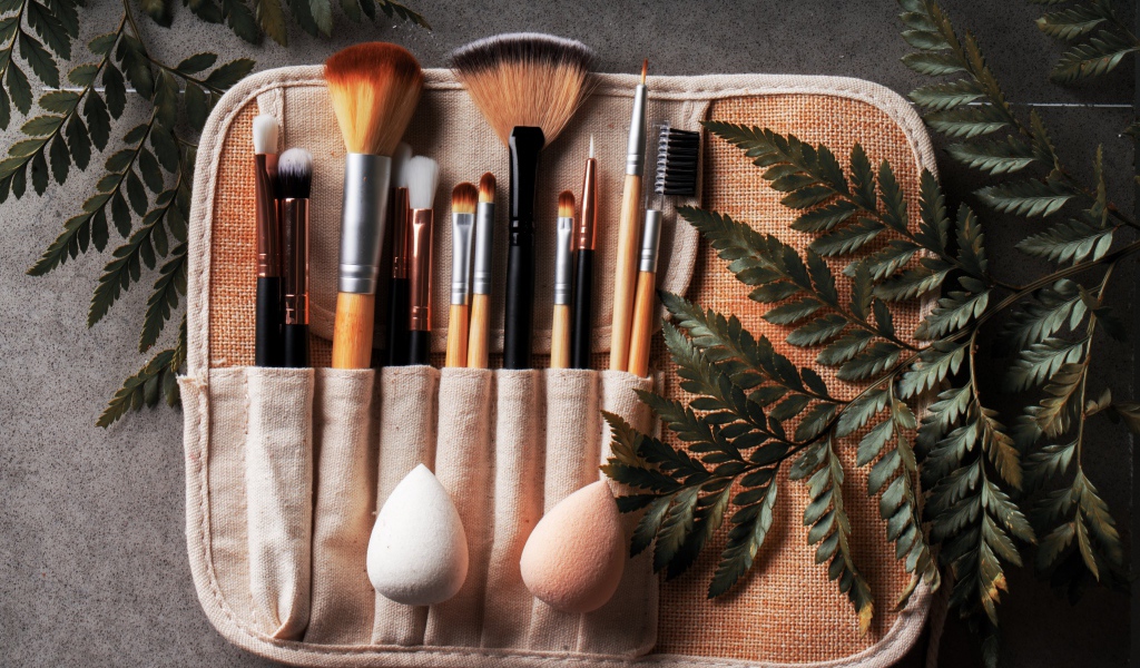 Кисти для макияжа в чехле на столе с листьями папоротника