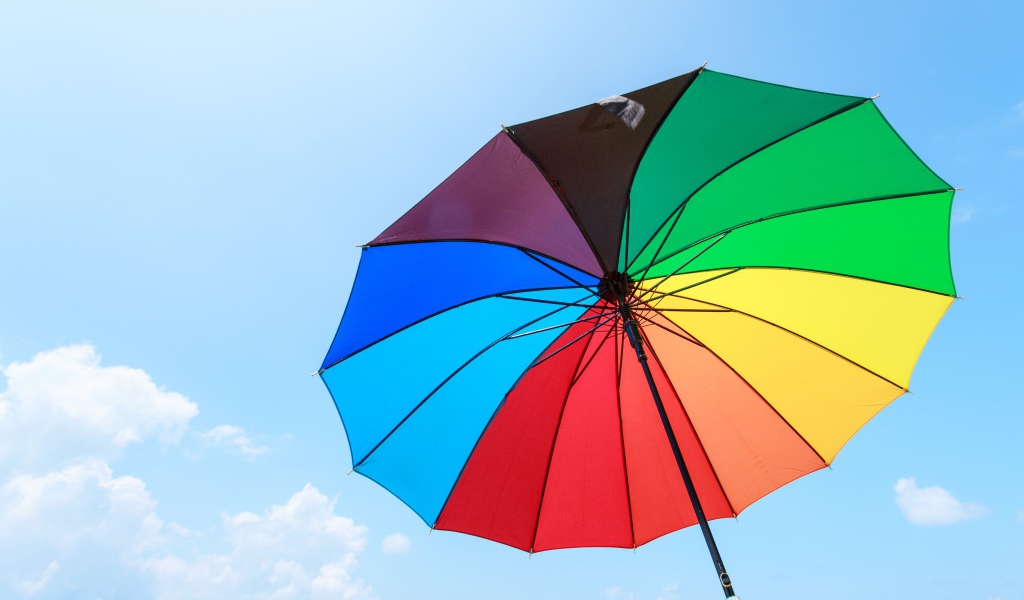 Разноцветный зонт на фоне голубого неба 