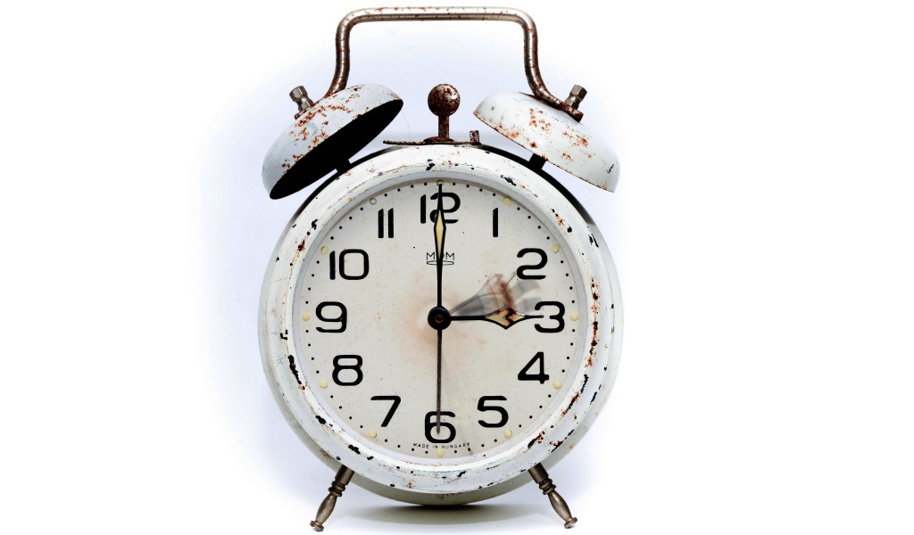 Старый потертый будильник на белом фоне