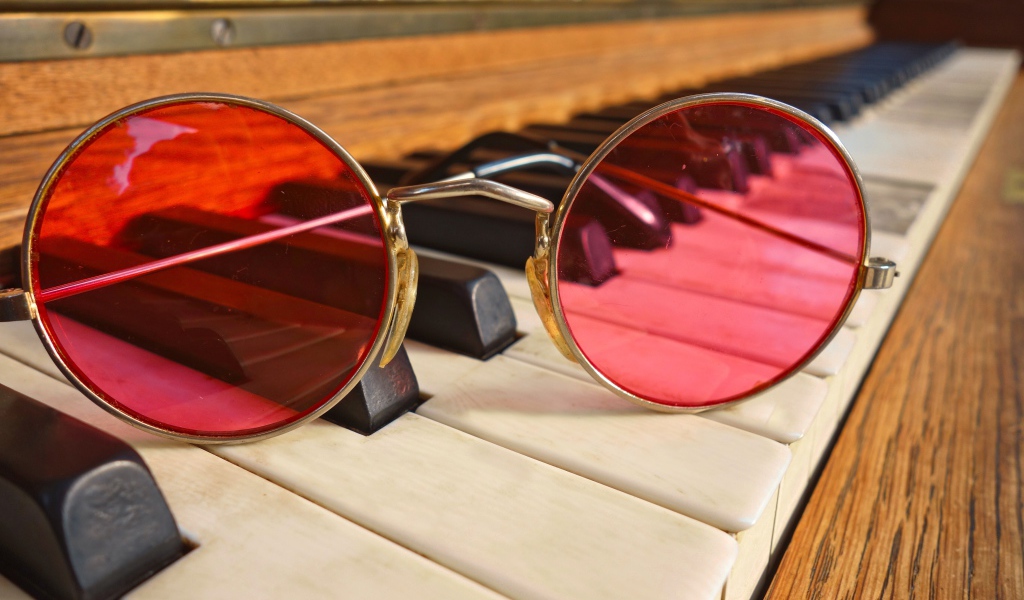 Розовые очки лежат на клавишах рояля