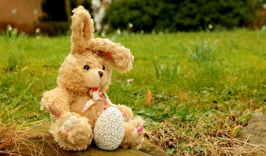 Игрушка заяц на камне в траве