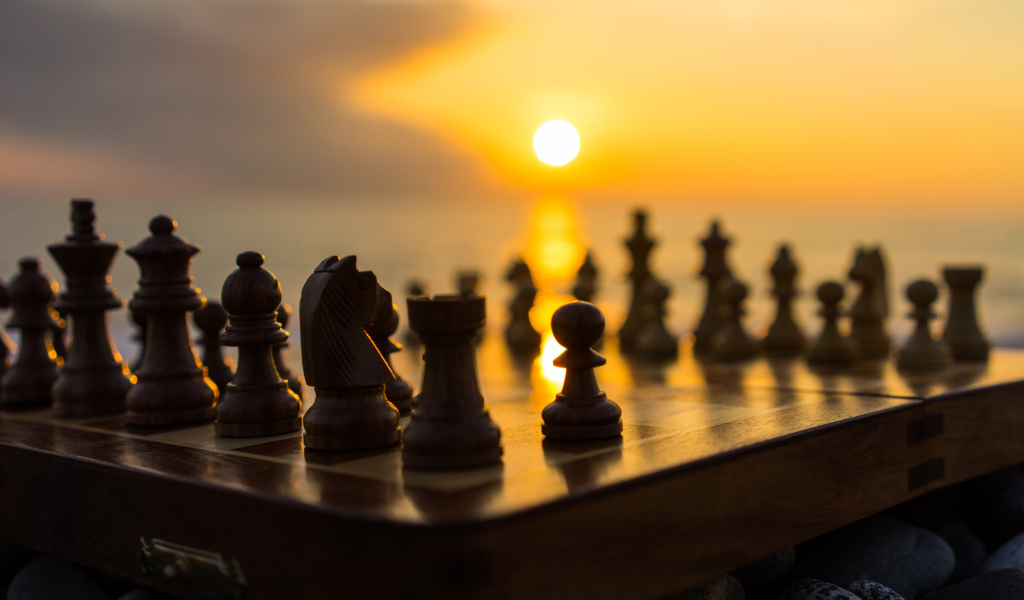 Wooden chess on a chessboard on a sunset background