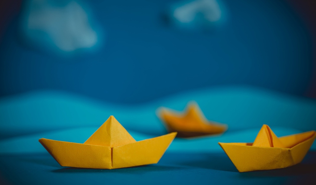 Желтые кораблики оригами на синем фоне