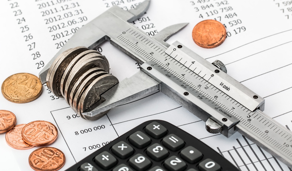 Монеты на столе с штангенциркулем и калькулятором