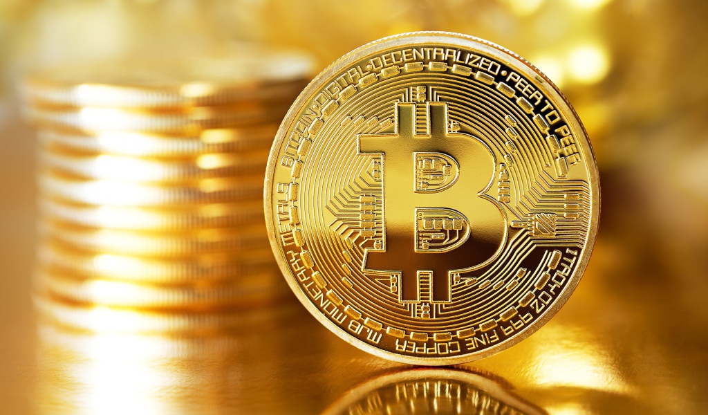 Золотая монета биткоин отражается в поверхности стола 