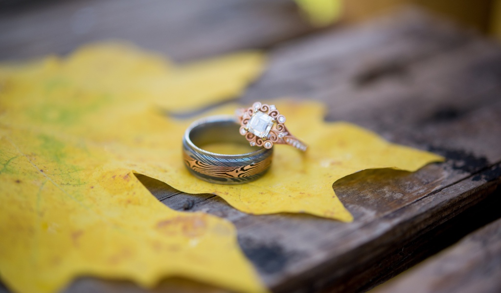 Золотые кольца с желтым листом на столе 