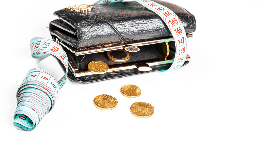 Черный кожаный кошелек с монетами и сантиметром на белом фоне