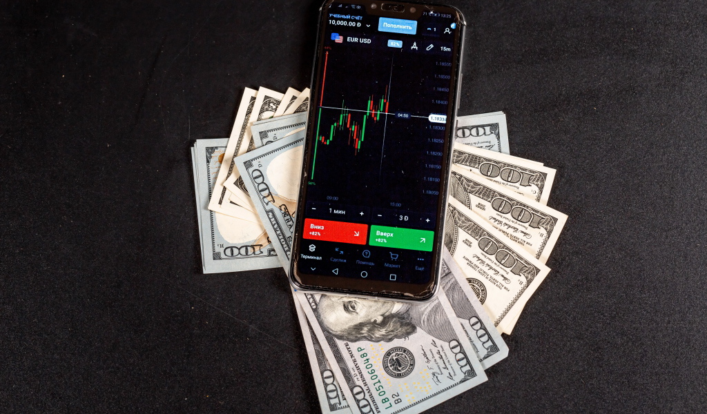 Доллары и смартфон на сером столе 