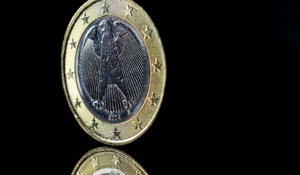 Монета евро стоит на ребре на черном фоне 