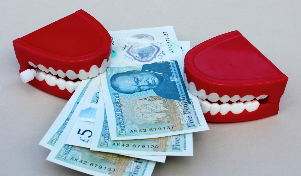 Два держателя денег в форме челюсти с купюрами на сером фоне