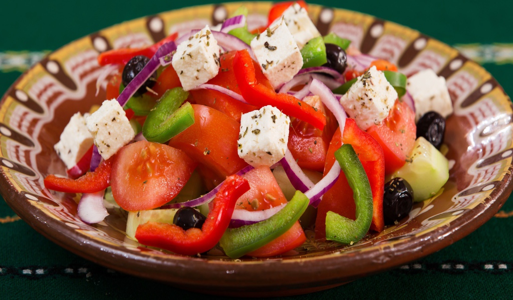 Аппетитный греческий салат в тарелке на столе