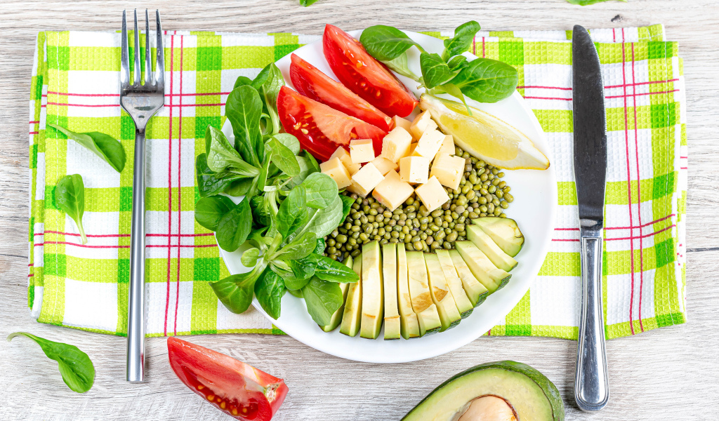 Аппетитные  свежие овощи с сыром и лимоном на тарелке 