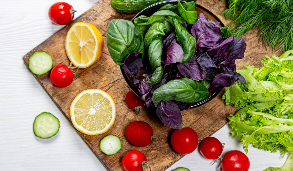 Базилик на столе с зеленью, помидорами и лимоном