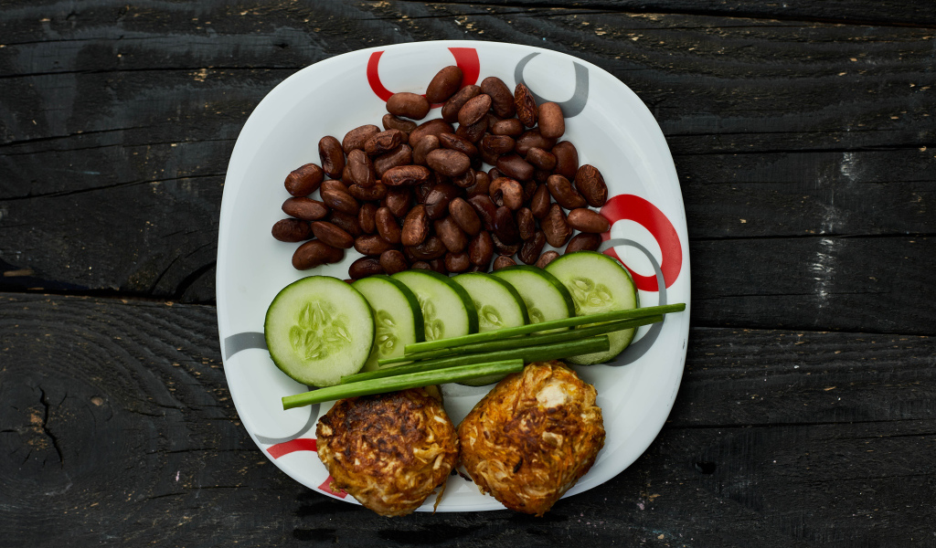 Фасоль на тарелке с оладьями и огурцами 