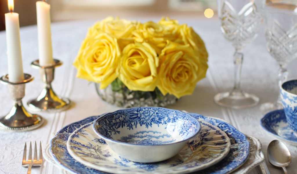 Красивая посуда на столе с букетом роз и свечами