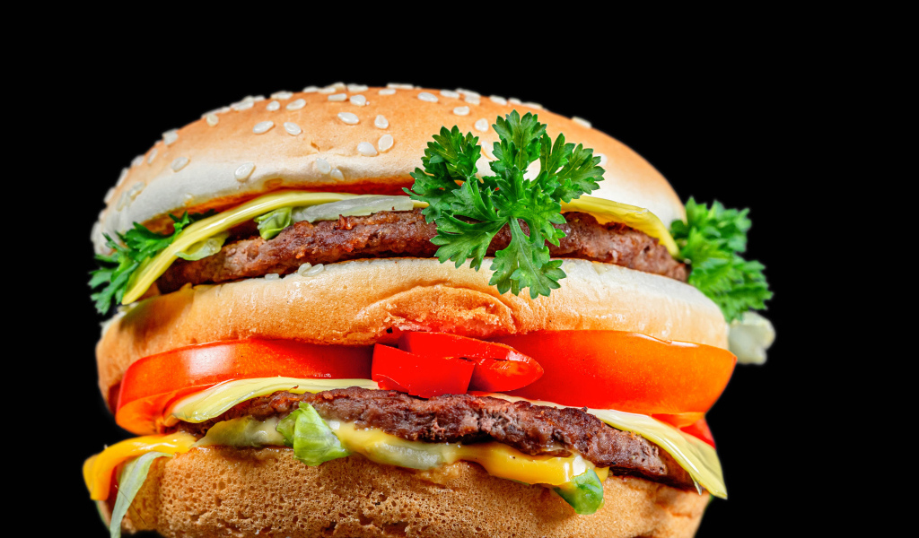 Большой гамбургер с котлетой на черном фоне