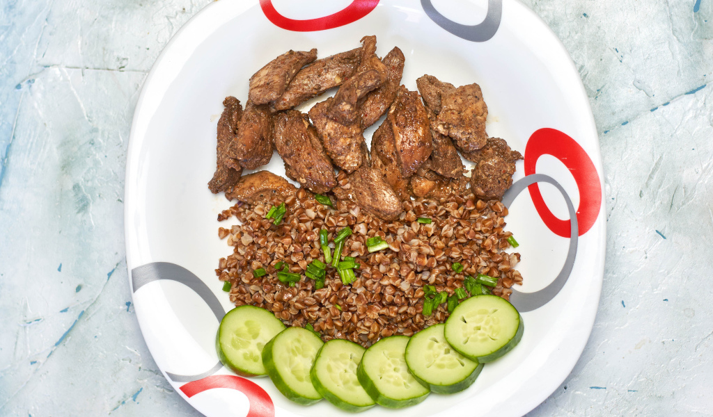 Гречка на тарелке с мясом и огурцами