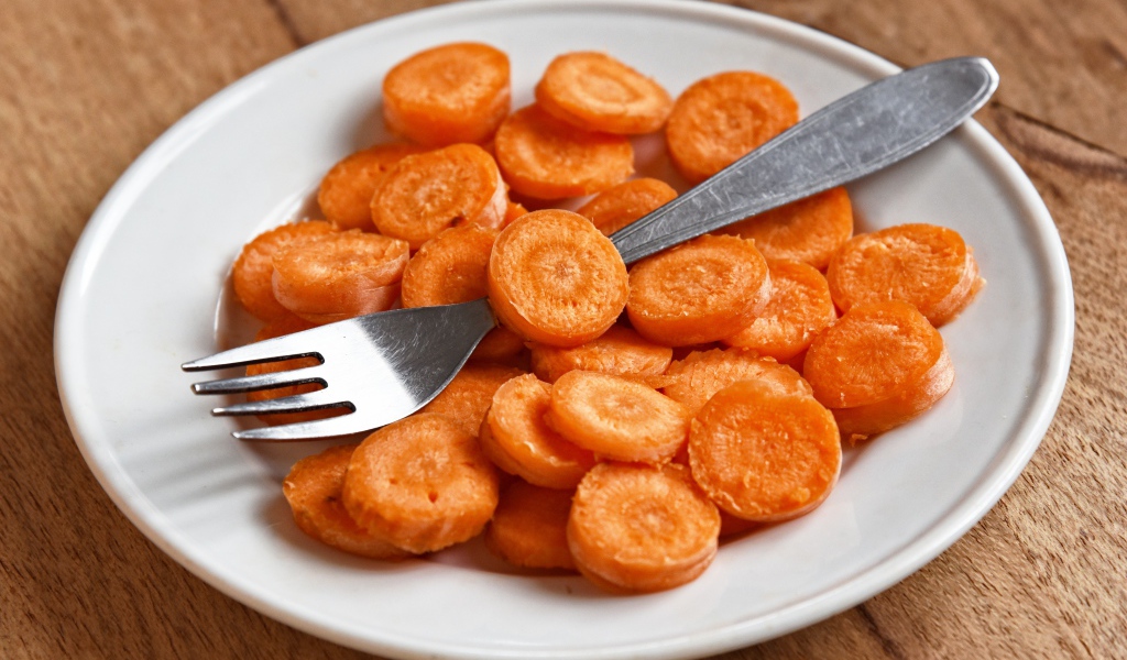 Морковь кружочками на белой тарелке с вилкой