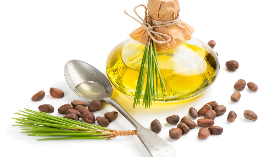 Кедровое масло на белом фоне с орехами и ложкой