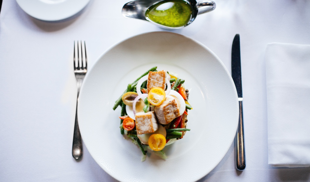 Салат из куриного филе с овощами на белой тарелке