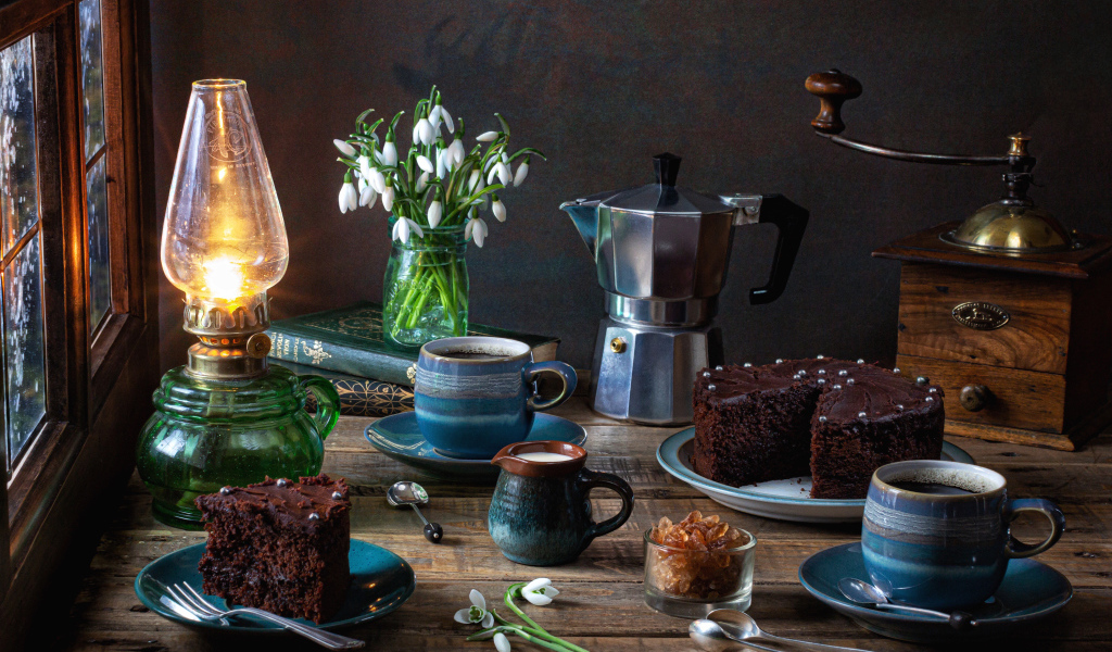 Шоколадный торт на столе с кофе, букетом подснежников и лампой