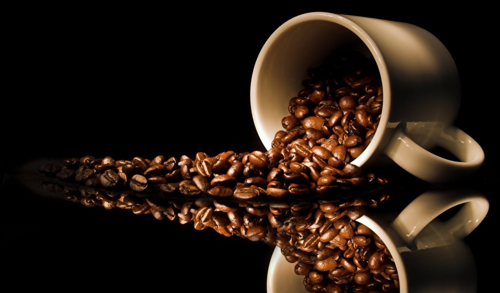 Кофейные зерна рассыпаны с белой кружки на стол