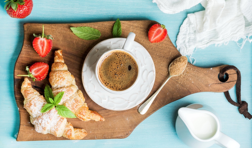 Чашка кофе на доске с клубникой и круассанами