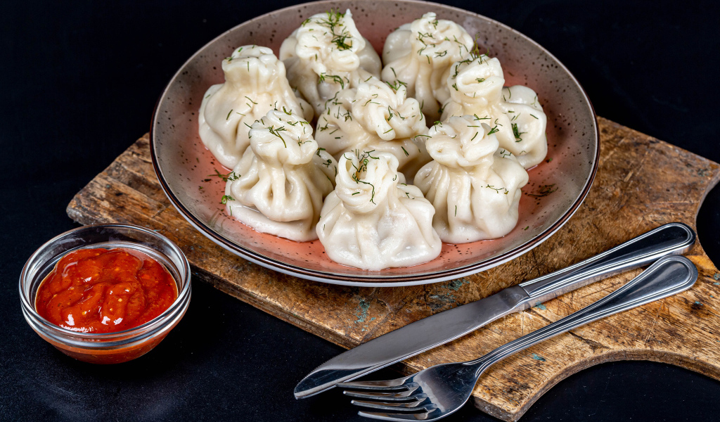 Вкусные горячие хинкали на столе с соусом