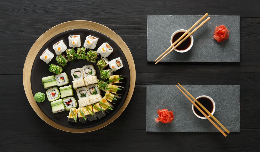 Вкусные  роллы на столе с соевым соусом и палочками 