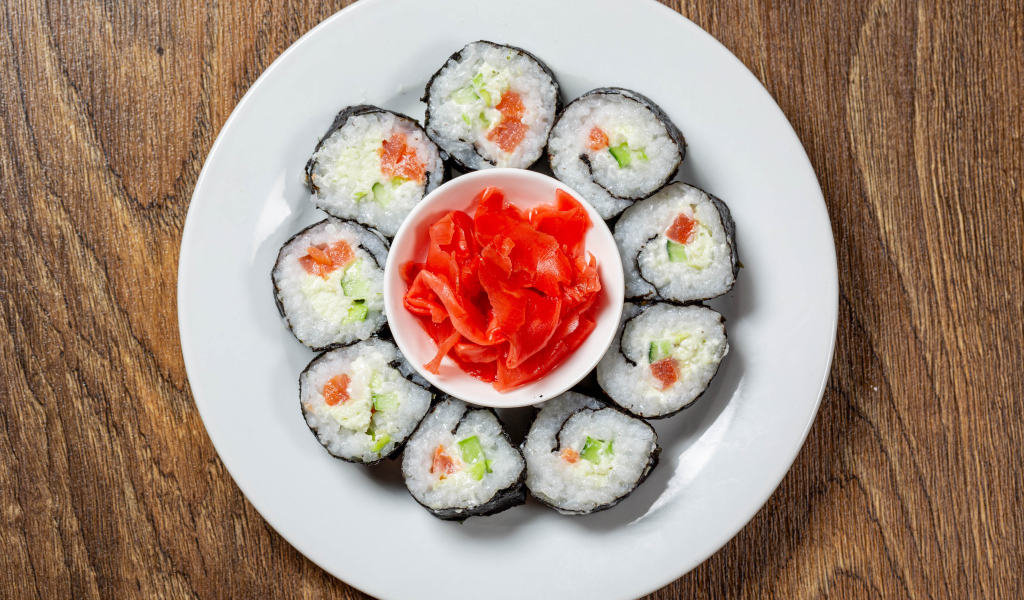 Вкусные суши на большой белой тарелке с имбирем