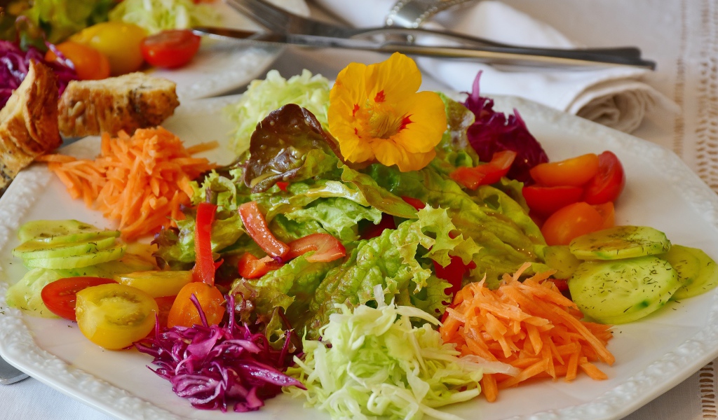 Салат из свежих овощей и зелени на большой белой тарелке 