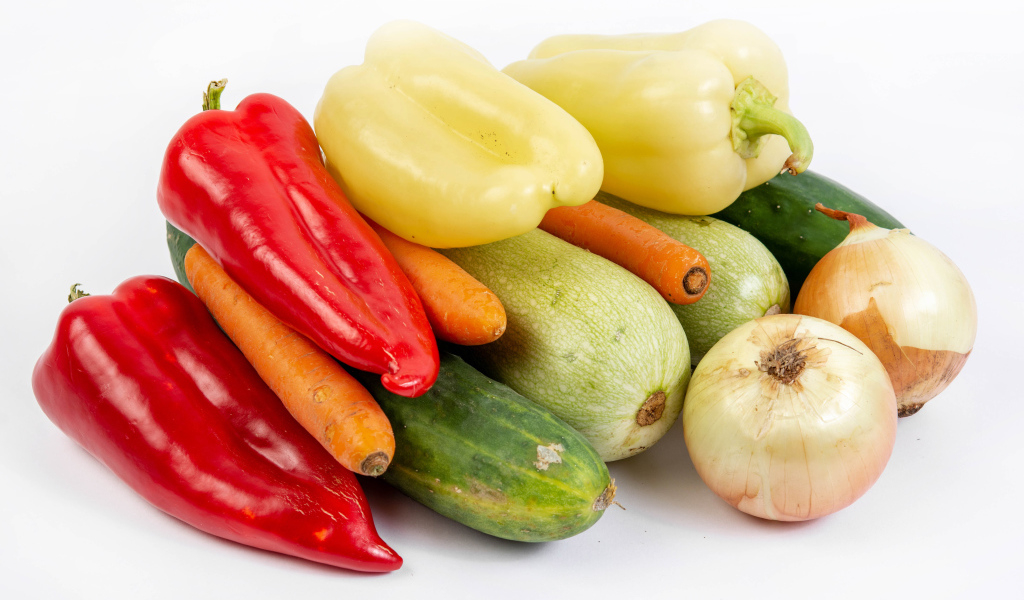 Свежие кабачки, огурцы, морковь, перец и лук на белом фоне