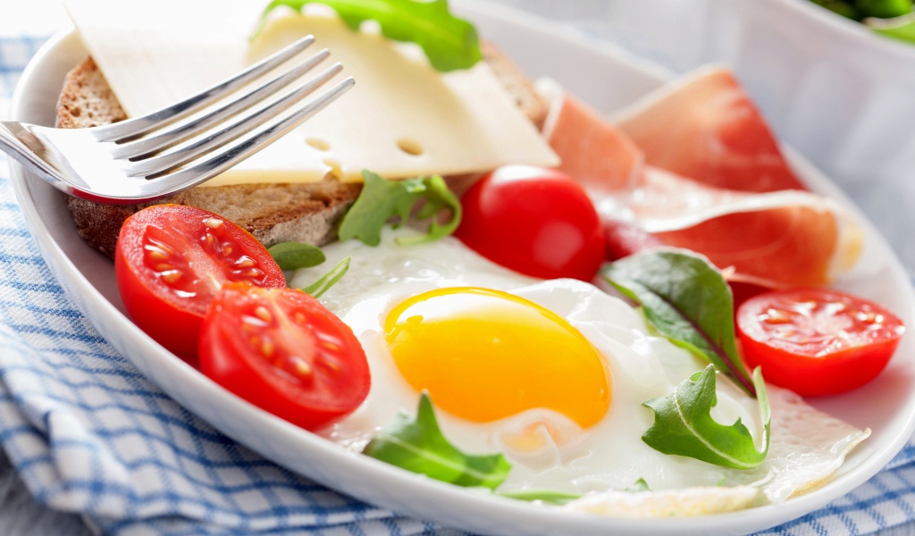 Яичница с помидорами на тарелке с ветчиной и бутербродом