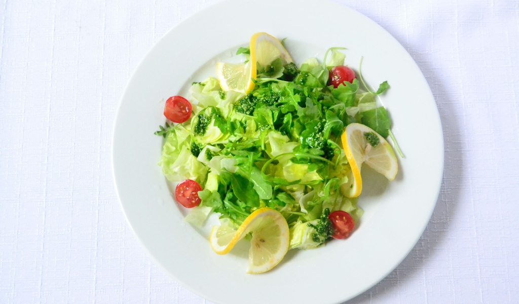 Салат из зелени с лимоном на белом фоне 