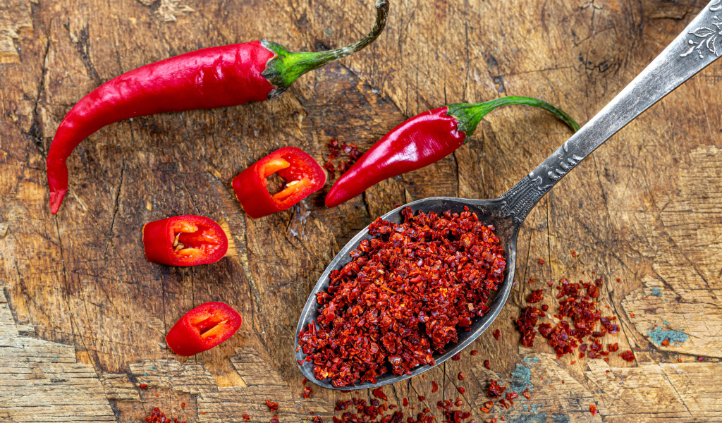 Молотый красный перец на ложке на столе 