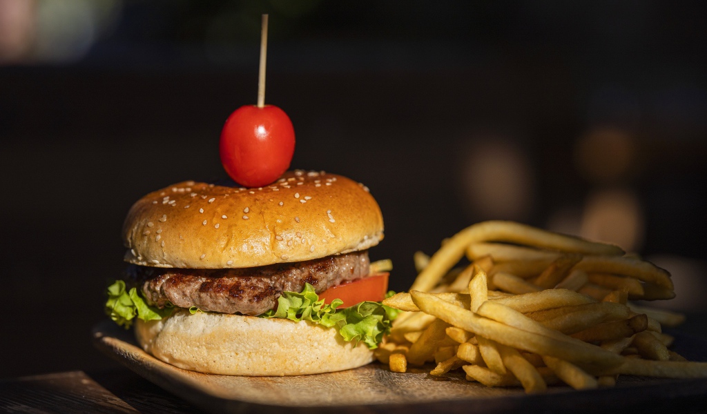 Гамбургер с помидором на доске с картофелем фри 