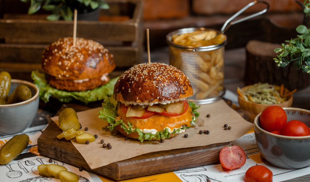 Hamburgers on the table with tomatoes, french fries and pickles