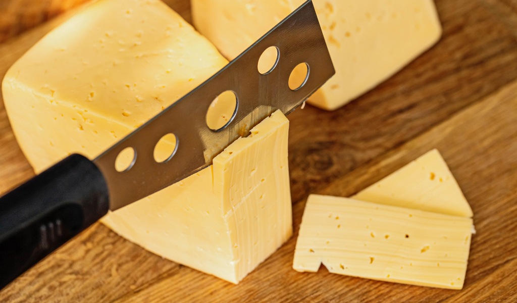 Твердый сыр с ножом на столе