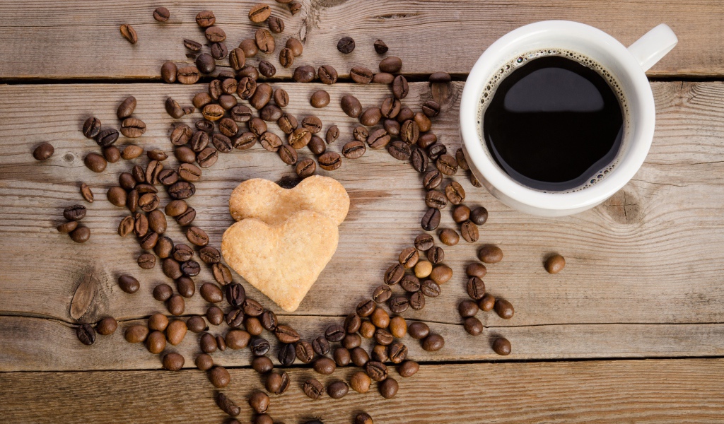 Печенье в форме сердца на столе с зернами и чашкой кофе 
