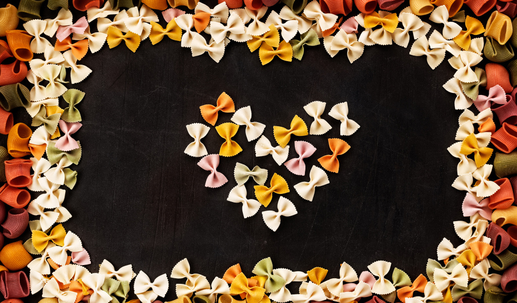 Сердце из разноцветных макарон на черном столе 