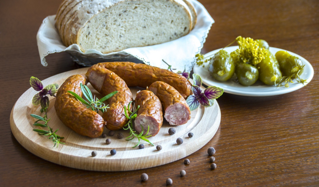 Домашняя колбаса на столе с хлебом и маринованными огурцами