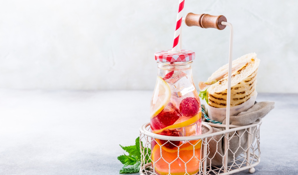 Банка с лимонадом в маленькой корзине с сэндвичем 