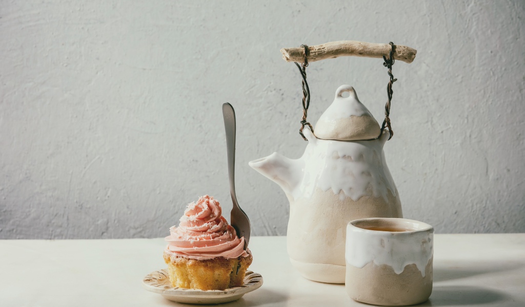 Чайник с чашкой на столе с кексом