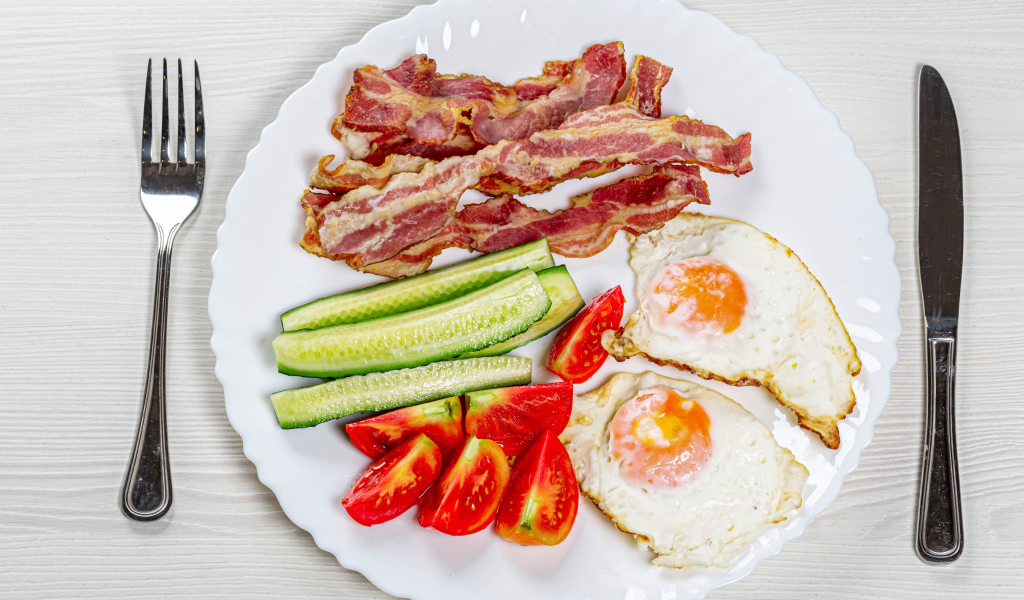 Большая белая тарелка с беконом, огурцами, помидорами и яичницей 
