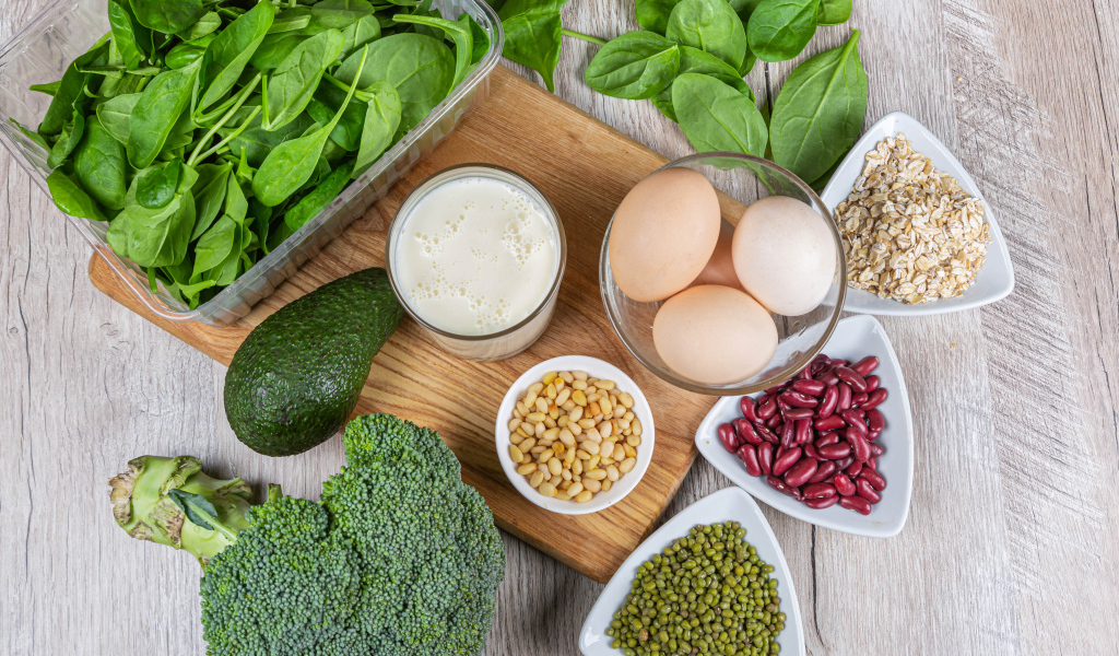 Бобовые, авокадо, базилик, яйца молоко и брокколи на столе