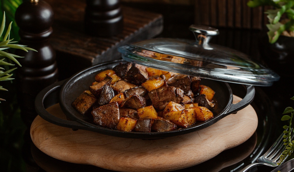 Печень с картофелем в сковороде на столе