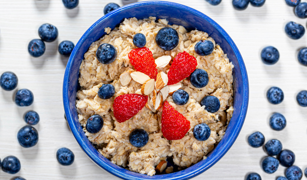 Овсяная каша в тарелке с ягодами черники и клубники 