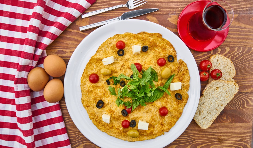 Омлет на столе с чаем, помидорами, яйцами и хлебом