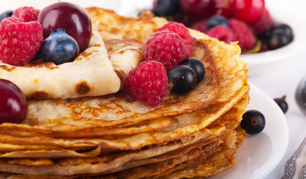 Pancakes with blueberries and raspberries on a white plate